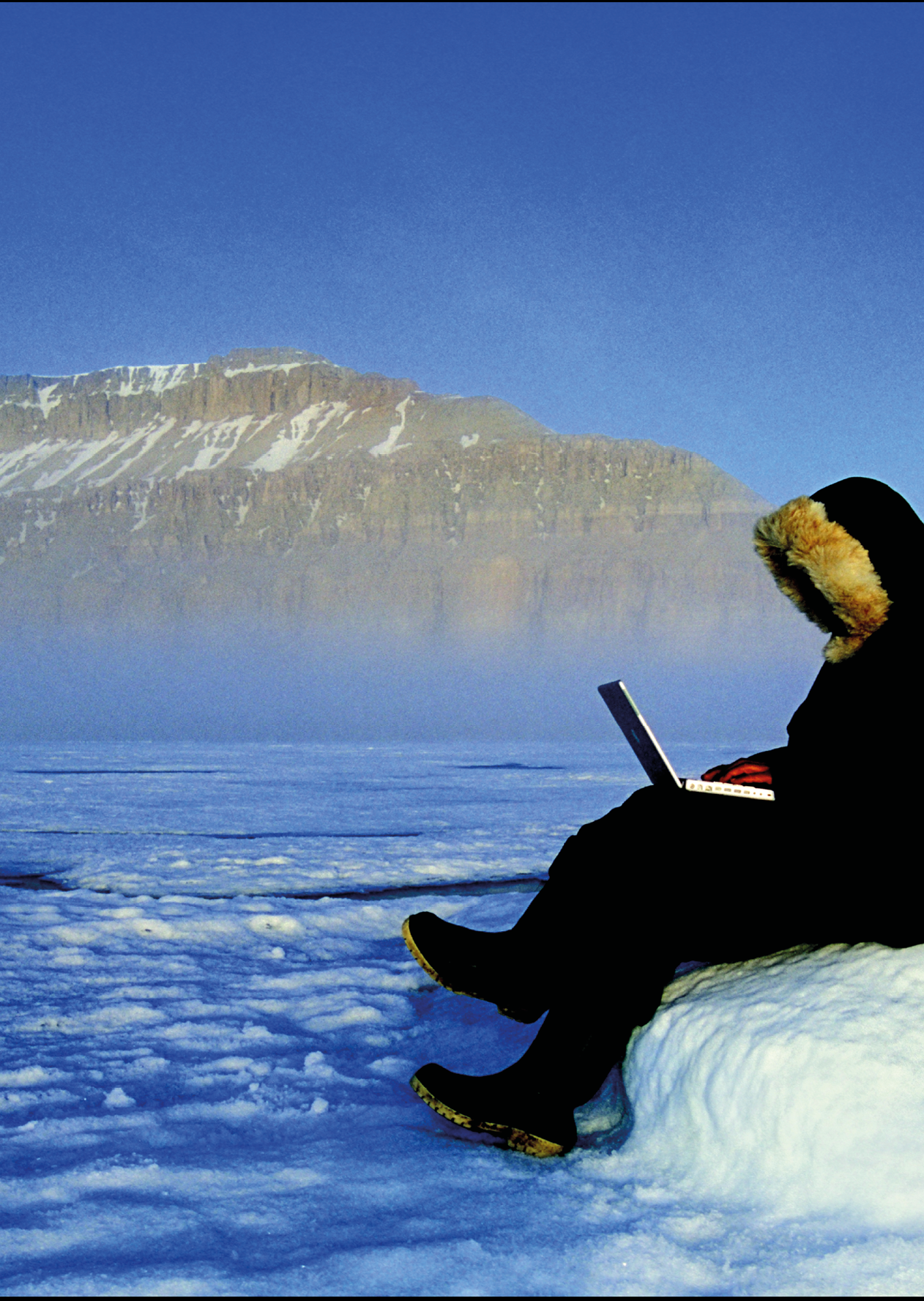 Japanese man dressed in Inuit clothing using a laptop computer 