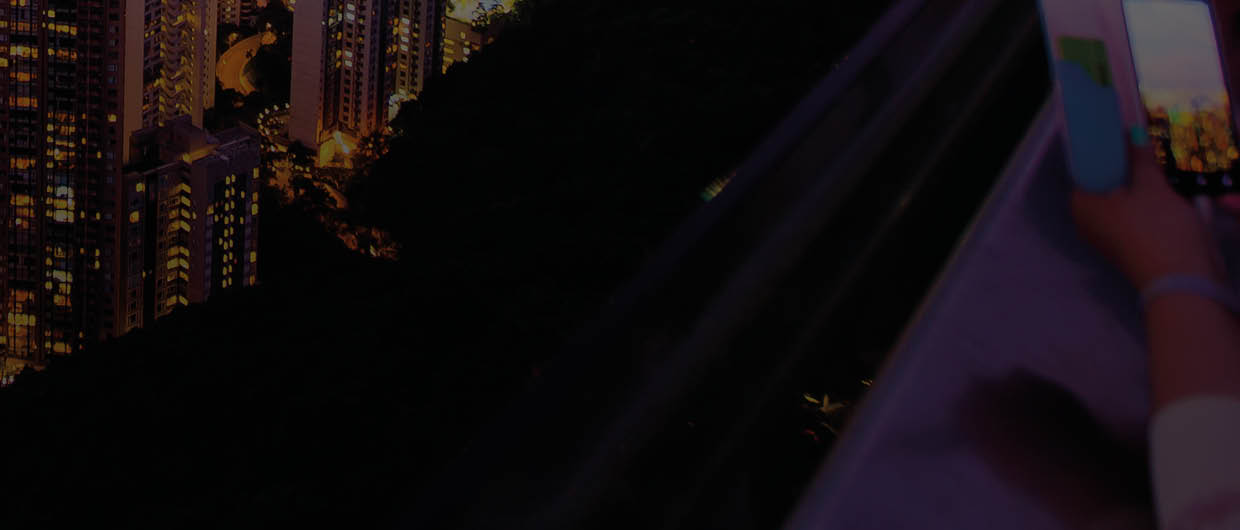 Tourists Photograph the Hong Kong skyline and Victoria Harbor from Victoria Peak at sunset 