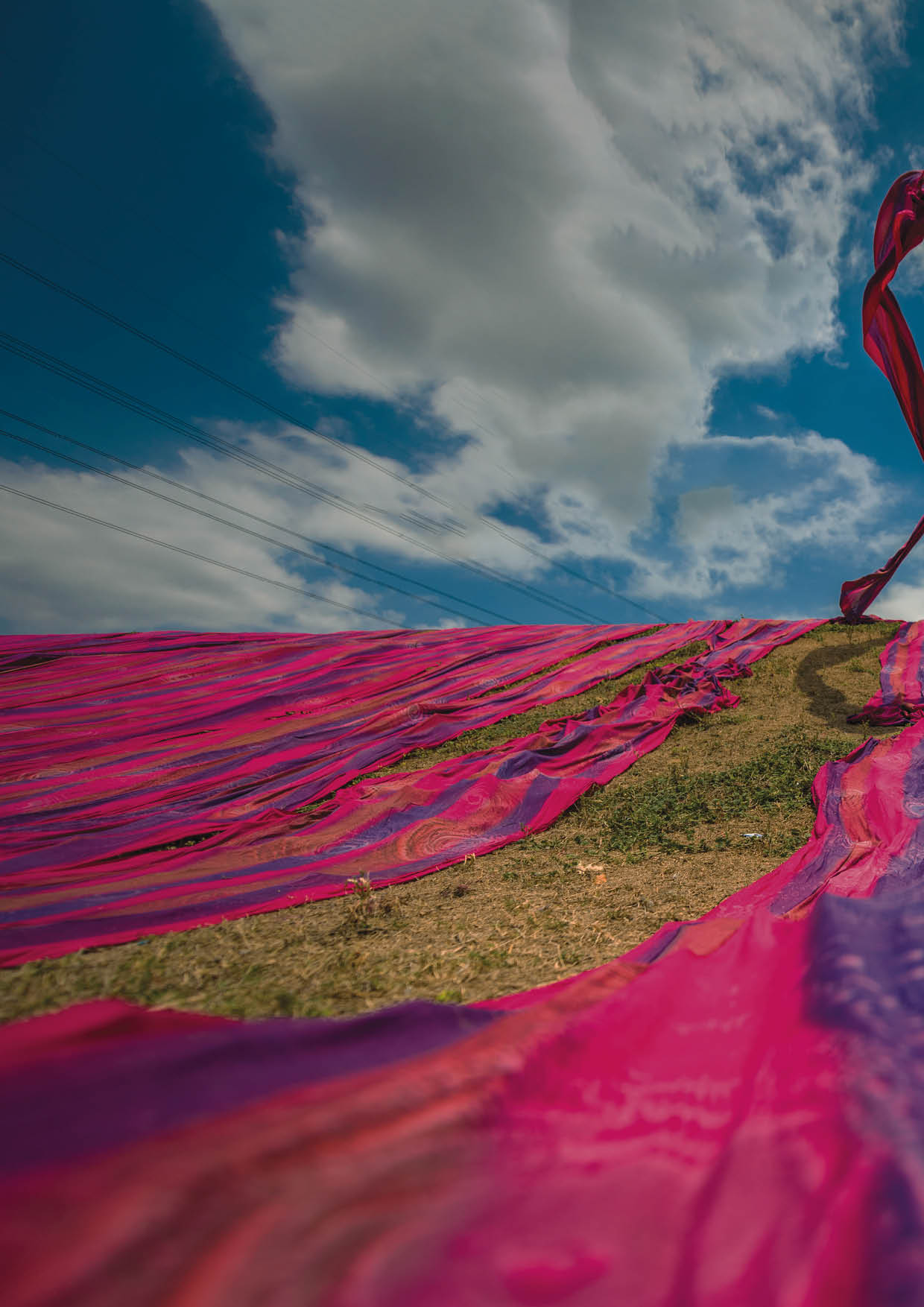 Long rolls of traditional fabric rolled down a hill to dry in the sun, creating a sea of color, Indonesia. ©Chue Ardi RH 1A and 1B cover image