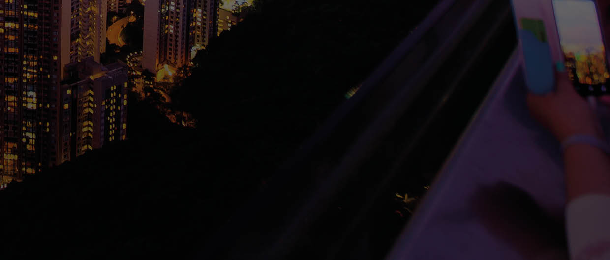 Tourists Photograph the Hong Kong skyline and Victoria Harbor from Victoria Peak at sunset.