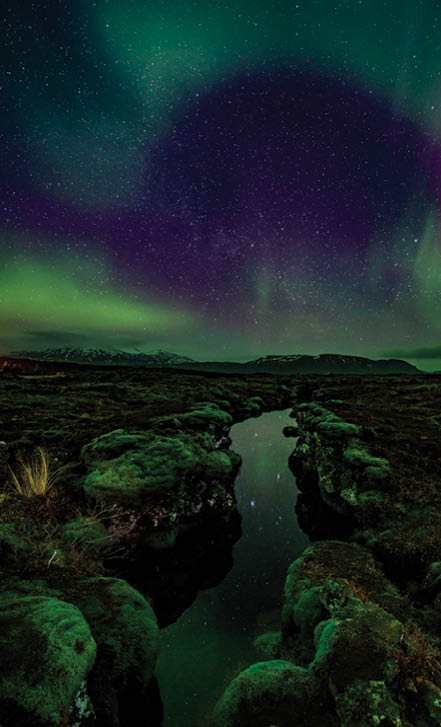 Aurora over the Silfra rift on the tectonic plates which straddle Iceland. The rift is full of gin clear water which is reflecting the aurora.