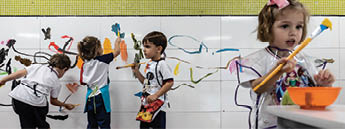 Young girls and boys paint their own artwork on a wall at their school in Belo Horizonte, Brazil.