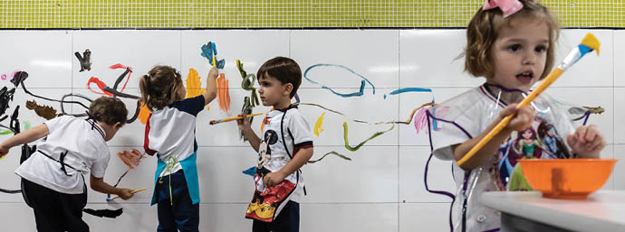 Young girls and boys paint their own artwork on a wall at their school in Belo Horizonte, Brazil.