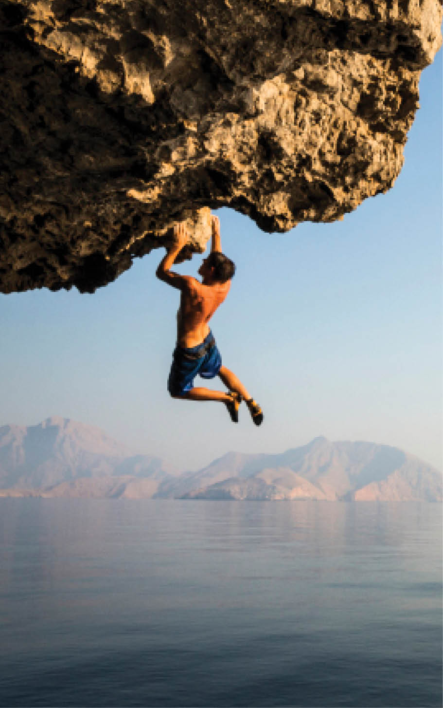 A climber dangles from an overhang in Oman.