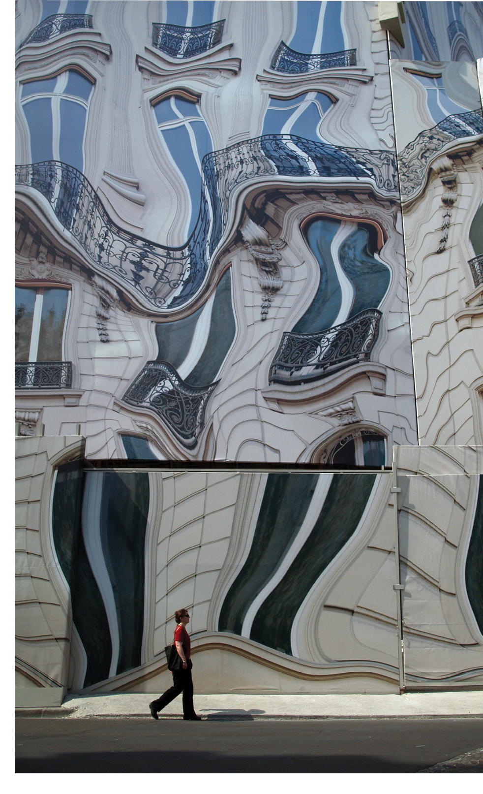 A tourist walking in front of a two dimensional painting.