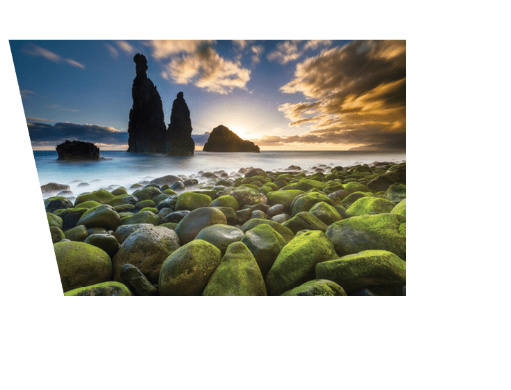 Green stones beach and giant rocks in the ocean at sunrise