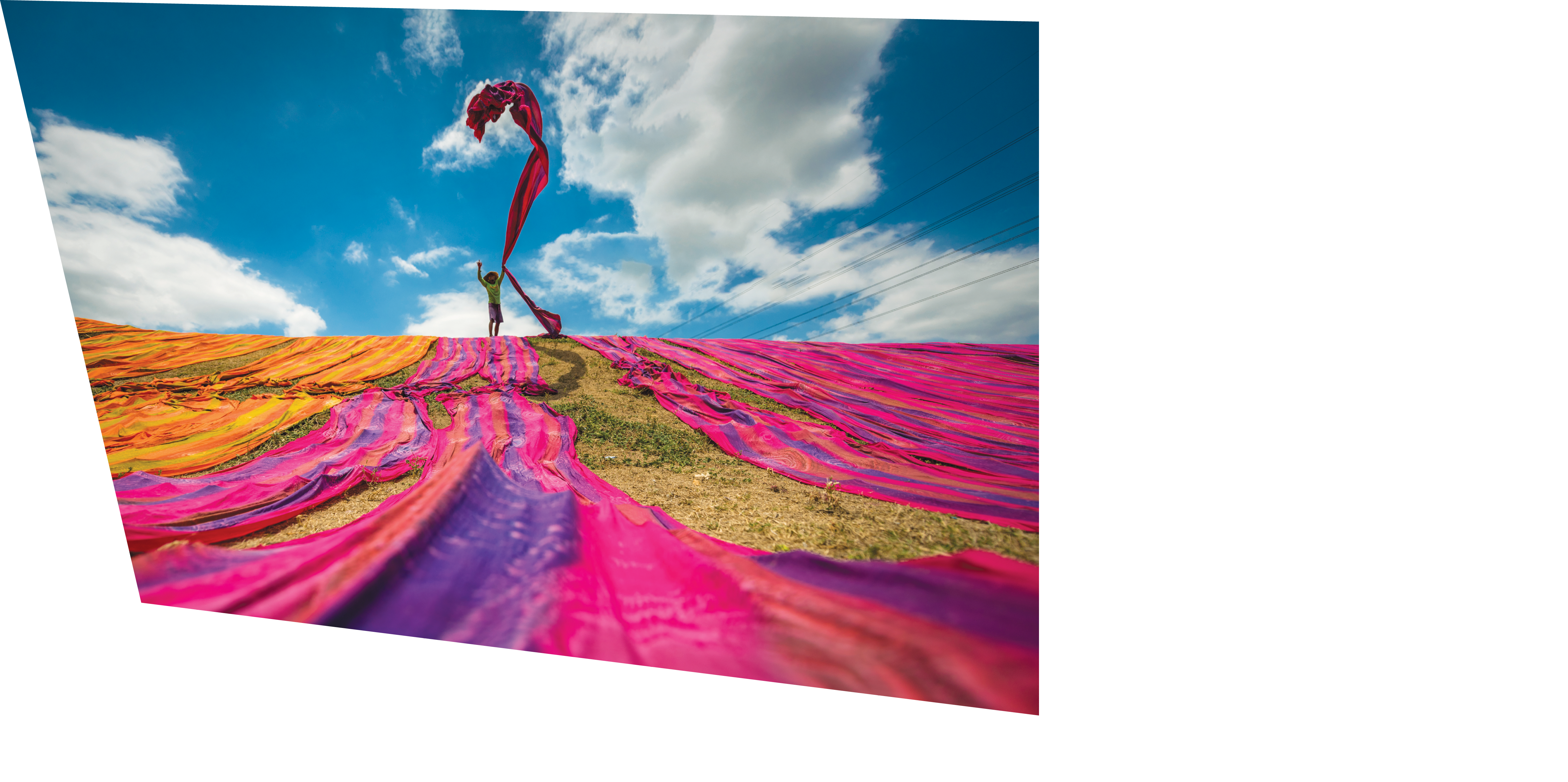 Long rolls of traditional fabric rolled down a hill to dry in the sun, creating a sea of color, Indonesia. ©Chue Ardi RH 1A and 1B cover image