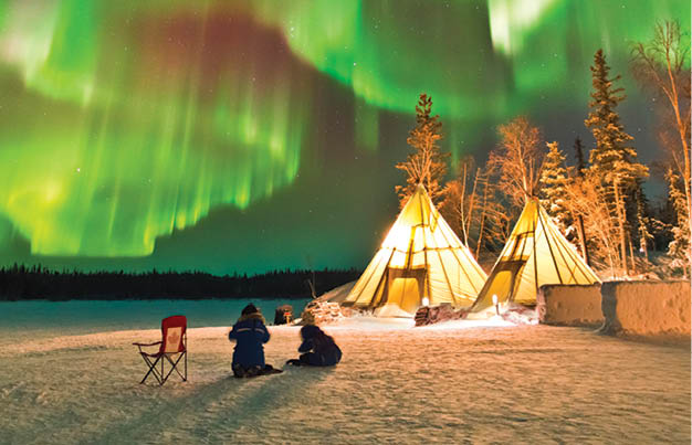Aurora Village in Yellowknife, Canada is a popular destination to see the Northern Lights up close. The camp’s glowing teepees complement the colorful ribbon of lights above.