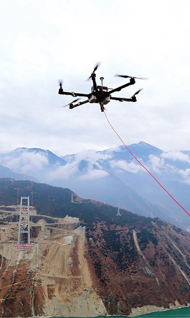 YA'AN, CHINA - DECEMBER 20: An unmanned aerial vehicle (UAV) towing a cable flies over the Dadu River to another side of the Ya'an-Kangding expressway bridge being built on December 20, 2016 in Ya'an, Sichuan Province of China. The Ya'an-Kangding expressway including a 1,100-meter-long main bridge over the Dadu River is being built. The workers used an unmanned aerial vehicle to stretch a cable connecting two sides of the bridge during the construction on Tuesday. (Photo by Zhang Jian/Chengdu Economic Daily/VCG)