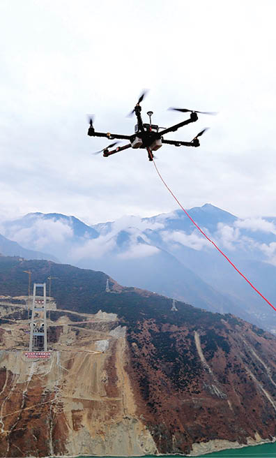 YA'AN, CHINA - DECEMBER 20: An unmanned aerial vehicle (UAV) towing a cable flies over the Dadu River to another side of the Ya'an-Kangding expressway bridge being built on December 20, 2016 in Ya'an, Sichuan Province of China. The Ya'an-Kangding expressway including a 1,100-meter-long main bridge over the Dadu River is being built. The workers used an unmanned aerial vehicle to stretch a cable connecting two sides of the bridge during the construction on Tuesday. (Photo by Zhang Jian/Chengdu Economic Daily/VCG)
