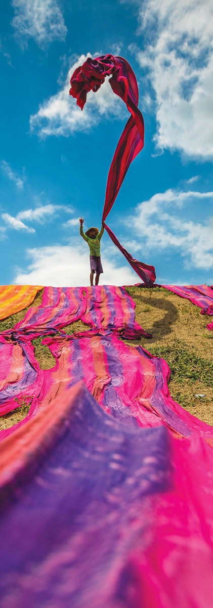 Long rolls of traditional fabric rolled down a hill to dry in the sun, creating a sea of color, Indonesia. ©Chue Ardi RH 1A and 1B cover image