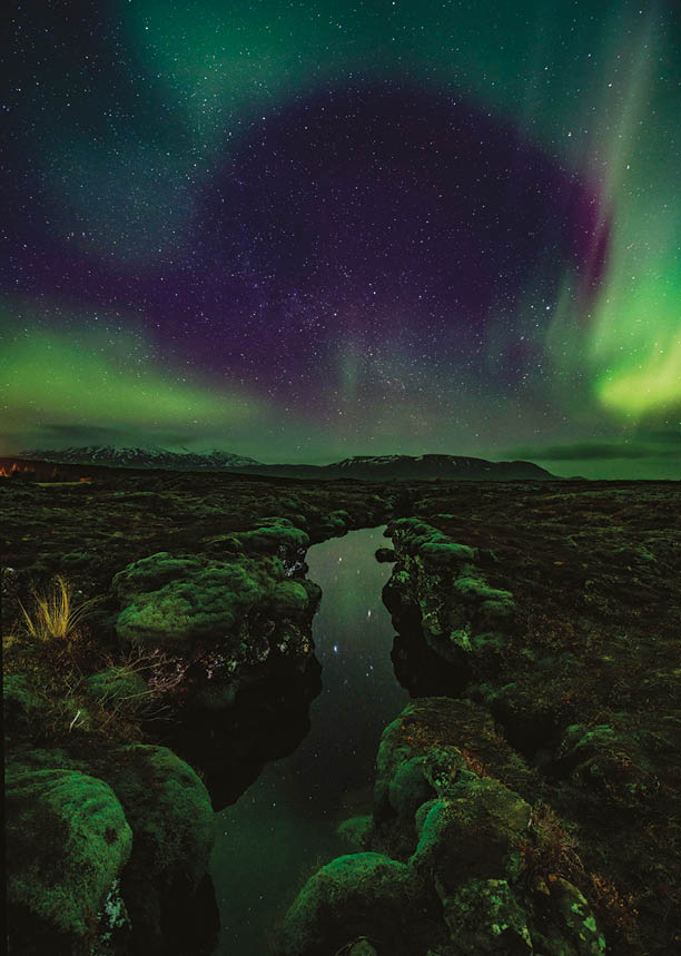 Aurora over the Silfra rift on the tectonic plates which straddle Iceland. The rift is full of gin clear water which is reflecting the aurora.