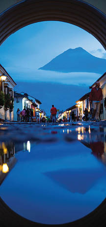  Twin Peaks of Antigua   The shadow of night is cast over Antigua as Volcán de Agua's silhouette dominates the horizon through Santa Catalina Arch, reflecting in the cobblestone rain puddles  Photo location: Santa Catalina Arch, Antigua, Guatemala  (Photo and caption by Beau Pilgrim National Geographic Photo Contest)