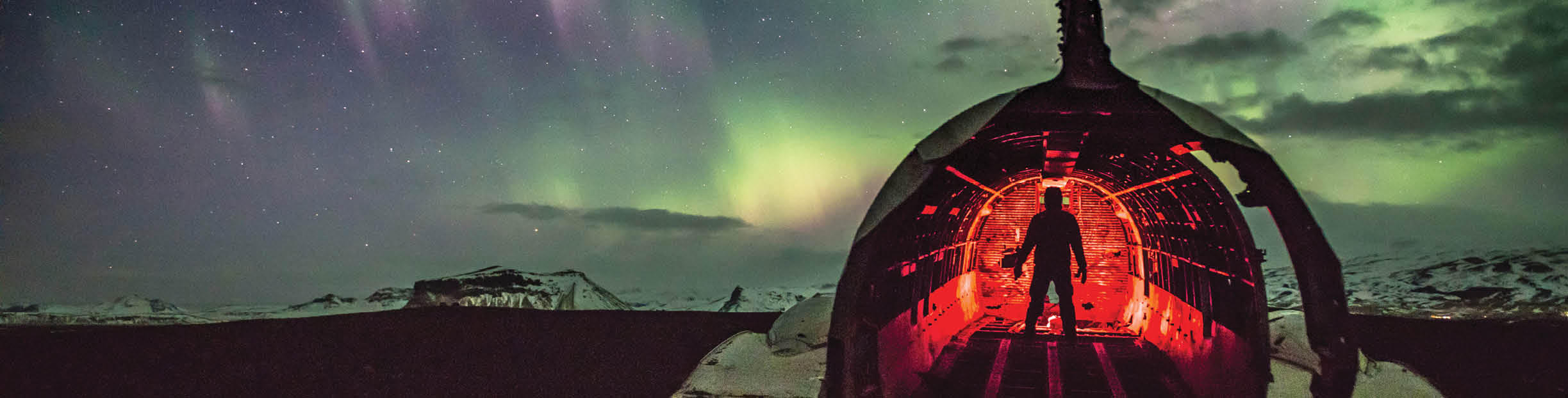 Silhouette Man In Illuminated Wrecked Airplane Against Sky At Night