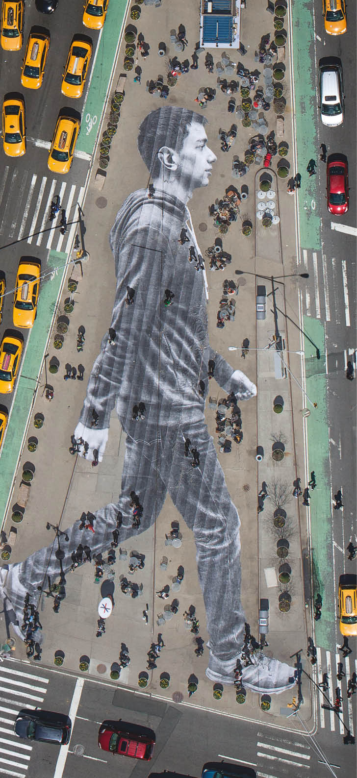 What you see on the cover of this week’s New York Times Magazine is real. The image is by the French artist JR, who is known for pasting giant photographs on urban surfaces all over the world. About six weeks ago, we met with JR to discuss a project for our Walking New York issue. Lately, JR’s work has been preoccupied with the theme of immigration. An installation at Ellis Island features large archival photographs of immigrants displayed throughout the island’s abandoned hospital. For this project, we decided we’d photograph recent immigrants and paste their images on the city’s streets, where they and other immigrants are often invisible. The pasting would be made in the heart of Manhattan, on Flatiron plaza, the triangle of pavement between Fifth Avenue, Broadway and East 23rd Street.  Earlier this month, JR photographed 16 people who arrived in New York within the last year and made their portraits while they walked down the streets of NoLIta. (Some of these portraits can been seen here.) For the cover, we zeroed in on Elmar Aliyev, a 20-year-old waiter at Old Baku, an Azerbaijani restaurant on Ditmas Avenue in Brooklyn. Elmar immigrated to the United States from Azerbaijan last August after he won the green-card lottery. He likes to walk in Central Park and around the Plaza, locations from his favorite movie, “Home Alone 2.” JR liked the way Aliyev swung his arms when he walked.  Aliyev’s picture was then printed on 62 strips of paper. On April 11, JR and his 20-person crew took these strips to Flatiron plaza and began affixing them to the ground at 4 a.m. The pasting took about three and a half hours and resulted in a 150-foot-tall image of Aliyev striding eastward. The sun came up. Pedestrians began to wander over Aliyev. Just as JR had predicted, they often walked right over him without even noticing.  To make out the image, you had to be high above. In the middle of the day, when the angles of shadow were favorable, JR went up in a helicopter and photographed the pasting, with all the cheerful and untidy street life of an early spring day in New York City happening on and around it.  That image is the one you see on the cover of the magazine — a gloriously massive portrait of one of the city’s 3.1 million immigrants, unseen by many of the people passing him on the street.