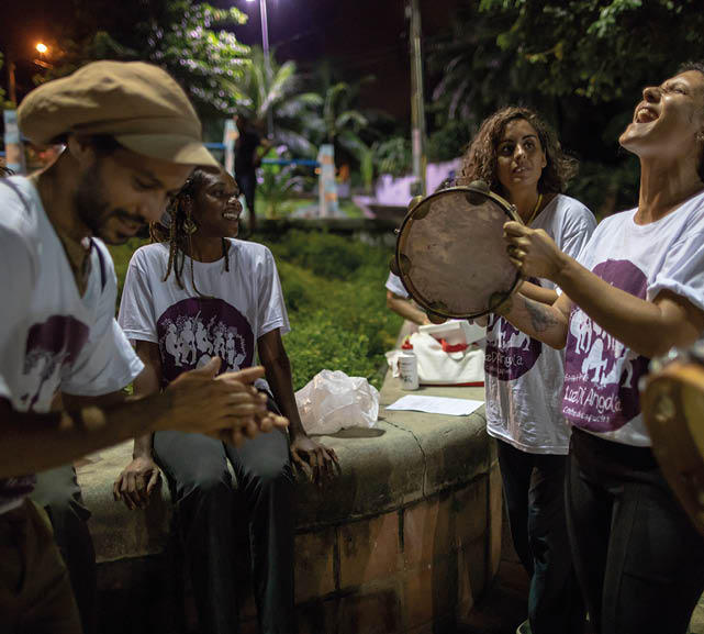 A group of musicians perform and sign traditional Coco music at a parl in Olinda, Brazil. The name “Coco" (Portuguese for "coconut") is a common Northeastern Brazilian slang for head, referring to the fact that song lyrics are often improvised. Coco is often performed with a repetitive musical beat and call and response singing reminiscent of Capoeira music. The music is commonly performed at traditional parties in the Northeast, such as weekend street parties and Carnival. Coco is also alternatively known as "embolada" (another slang word, meaning "entangling", referring to the fast, slurred, machine-gun style of singing). (Releases in R Capoeira , R Folder 2)