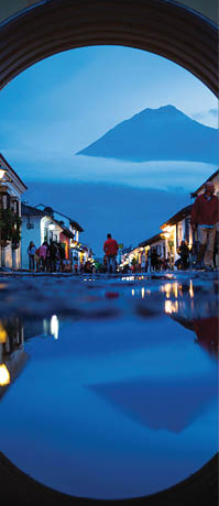  Twin Peaks of Antigua   The shadow of night is cast over Antigua as Volcán de Agua's silhouette dominates the horizon through Santa Catalina Arch, reflecting in the cobblestone rain puddles  Photo location: Santa Catalina Arch, Antigua, Guatemala  (Photo and caption by Beau Pilgrim National Geographic Photo Contest)