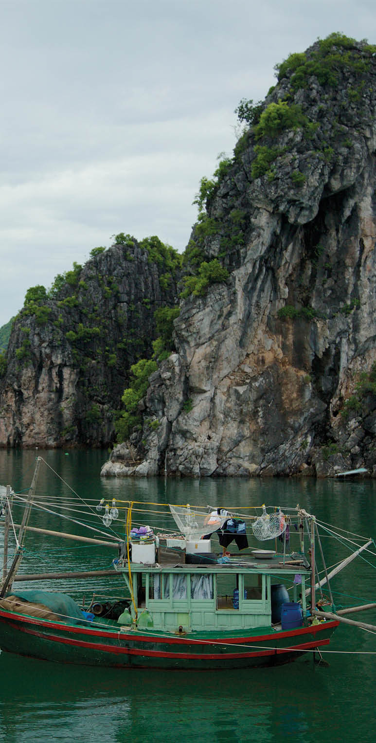 Fishing boat among the karst limestone islands in Halong Bay, Hanoi, Vietnam.