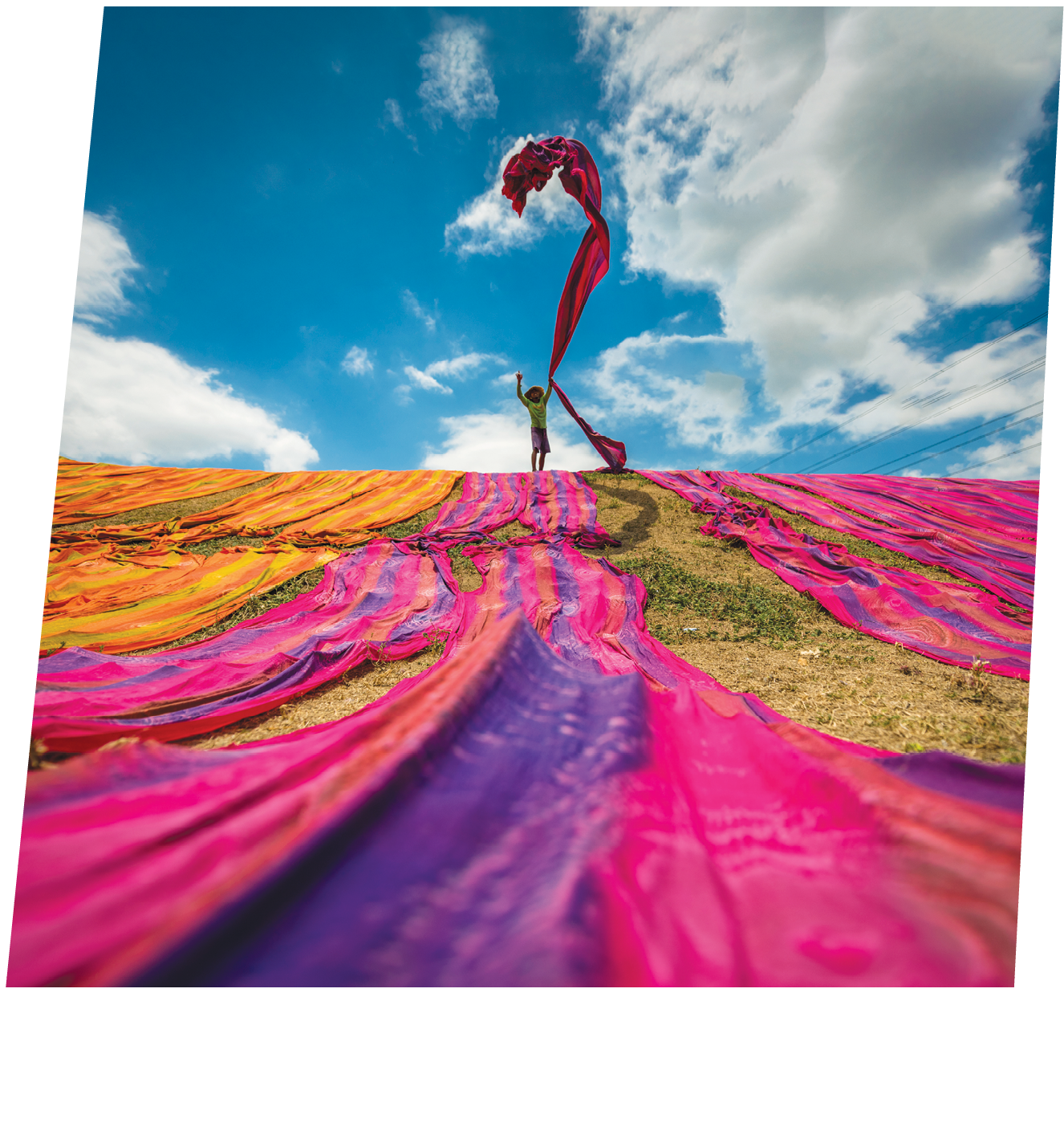 Long rolls of traditional fabric rolled down a hill to dry in the sun, creating a sea of color, Indonesia. ©Chue Ardi RH 1A and 1B cover image