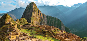 Machu picchu mountain view during sun rise with beautiful light and some tourists in the distance.