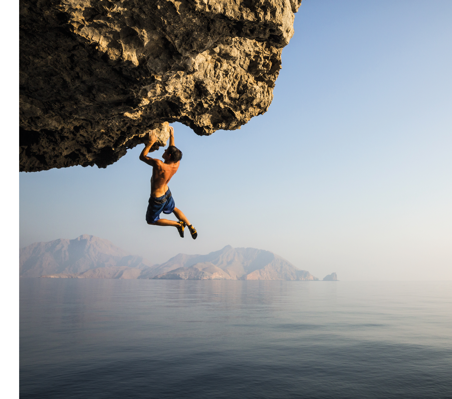 A climber dangles from an overhang in Oman.