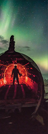 Silhouette Man In Illuminated Wrecked Airplane Against Sky At Night