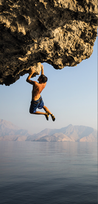 A climber dangles from an overhang in Oman.
