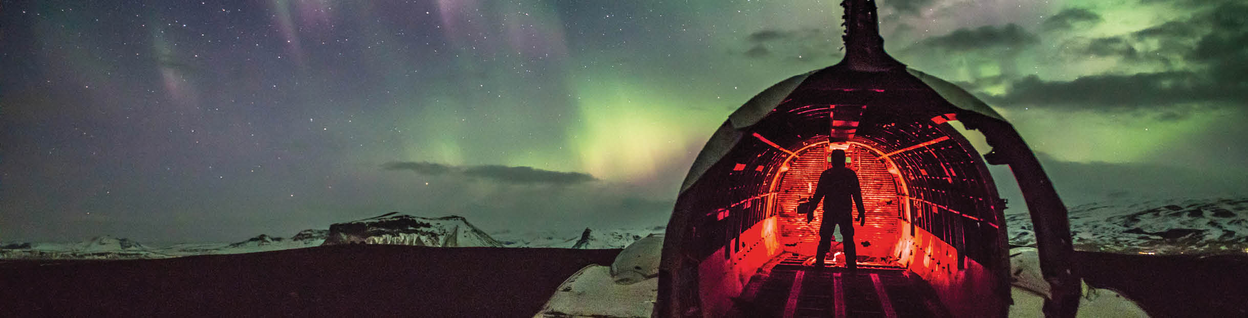 Silhouette Man In Illuminated Wrecked Airplane Against Sky At Night