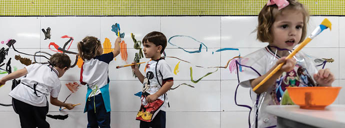 Young girls and boys paint their own artwork on a wall at their school in Belo Horizonte, Brazil.
