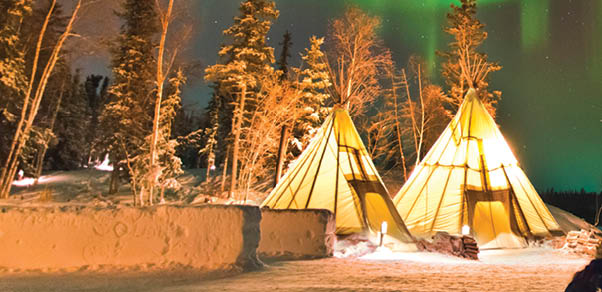 Aurora Village in Yellowknife, Canada is a popular destination to see the Northern Lights up close. The camp’s glowing teepees complement the colorful ribbon of lights above.
