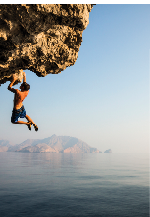 A climber dangles from an overhang in Oman.
