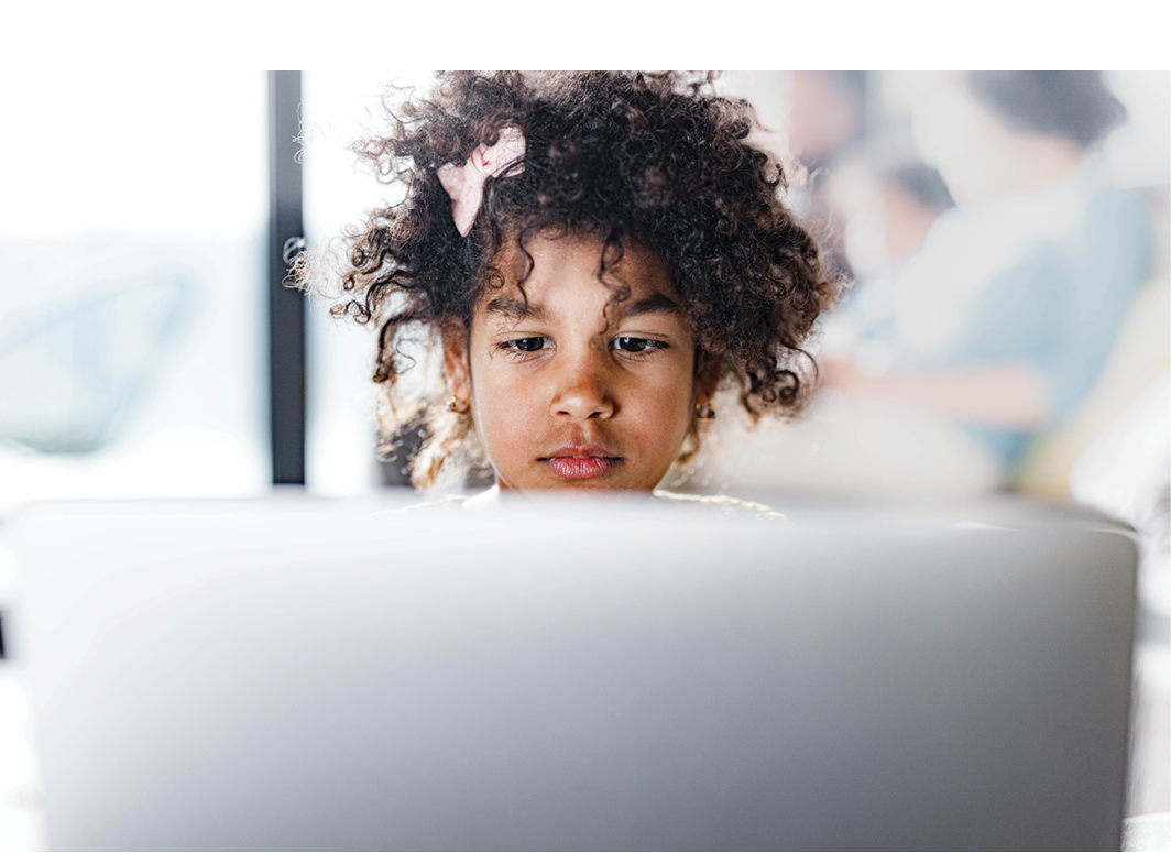 Cute African American girl surfing the Internet on a computer at home.
