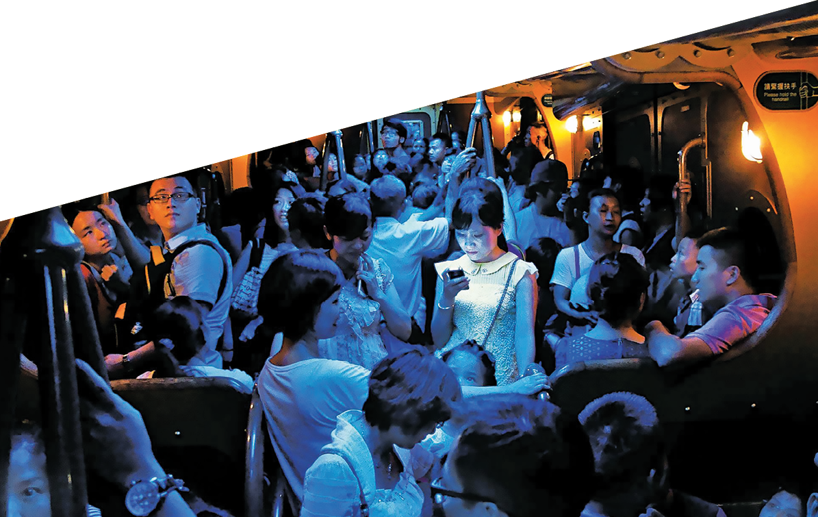 On a hot day in Hong Kong, people crowded into an air-conditioned train. When the lights dimmed, one young woman stood out, lost in the glow of her own digital world.